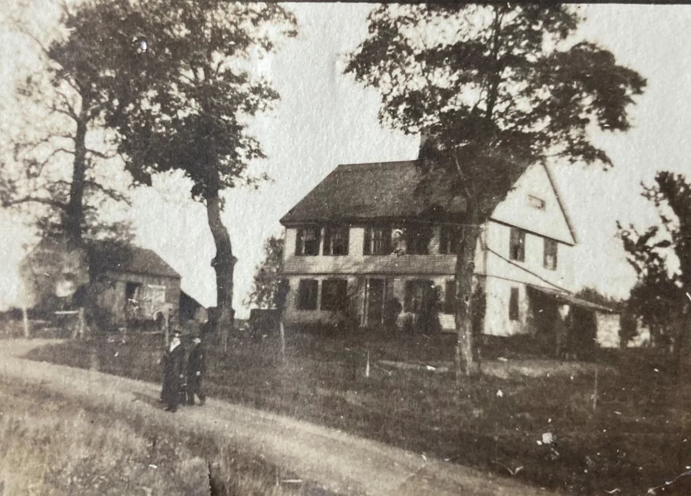 The Hamlin homestead in the White Oak section of Plainville, photographed in the later 1800's or early 1900's, with a barn and two figures standing along the road